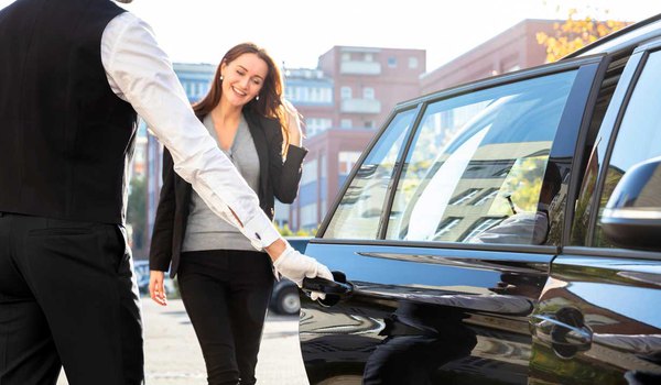 A professional transportation valet opens the car's door as a part of Central Texas Valet's transportation management services.