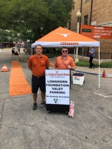 Two men standing behind a stand about the University of Texas Longhorn Foundation Football Parking