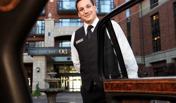 A professional hotel valet opens the car's door for parking management. 